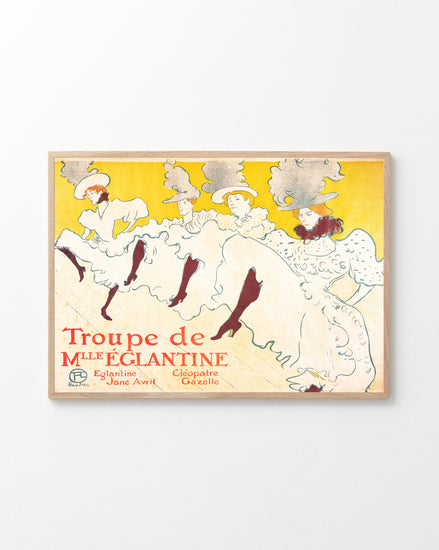 A framed poster titled La Troupe de Mademoiselle Eglantine by Henri de Toulouse-Lautrec features elegant dancers in flowing white dresses and elaborate hats against a bright yellow background, including performers Eglantine, Jane Avril, and Cléopâtre, evoking the Belle Époque era.