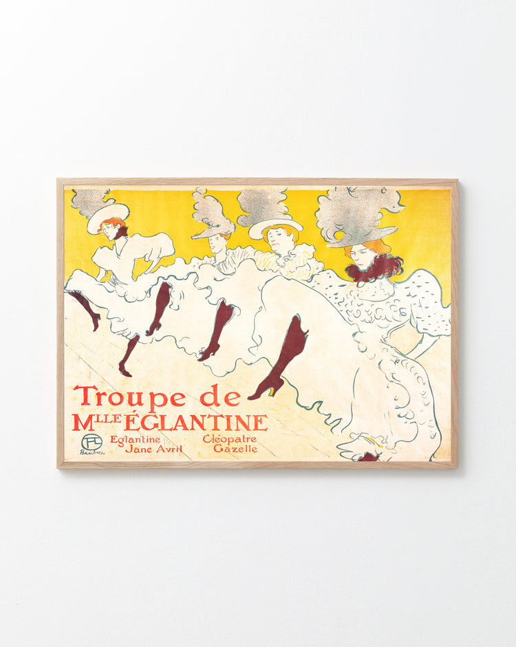 A framed poster titled La Troupe de Mademoiselle Eglantine by Henri de Toulouse-Lautrec features elegant dancers in flowing white dresses and elaborate hats against a bright yellow background, including performers Eglantine, Jane Avril, and Cléopâtre, evoking the Belle Époque era.