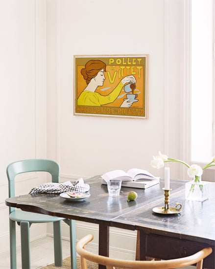 Dining room with a table and chairs, featuring a vintage-style poster on the wall.