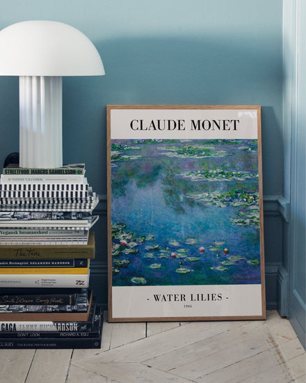 The Water Lilies by Claude Monet 1906 Poster leans against a teal wall next to a stack of books, with a white table lamp partially visible on the left, highlighting the famous Impressionist artwork.