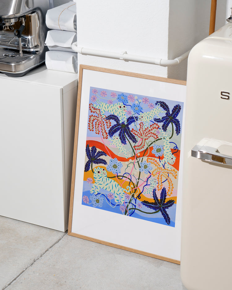 The Mumble Fizz Poster, featuring a colorful abstract design with vibrant blue, orange, pink, and green plants and swirls reminiscent of a playful tiger landscape, leans against a white kitchen cabinet. Nearby sits a cream-colored appliance and neatly stacked towels.