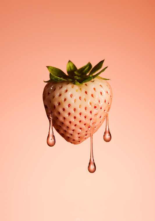 A stilllife photograph of a flawless white strawberry on a pretty pink background.