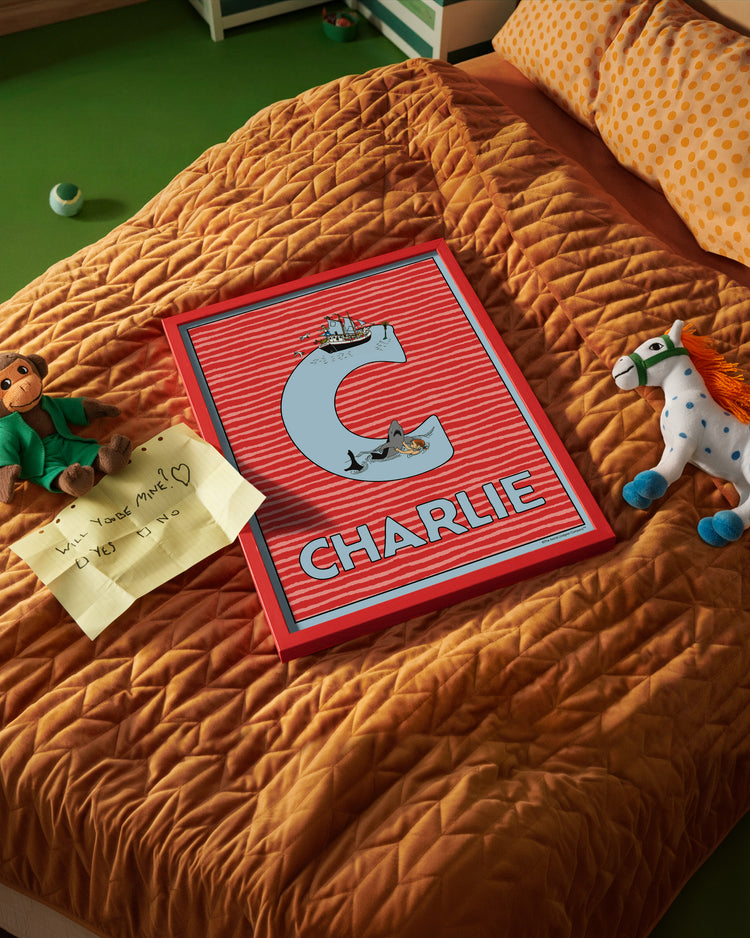 Pippi Longstocking name poster with the letter C and the name Charlie, placed on a neatly made bed in a bright kids’ room.