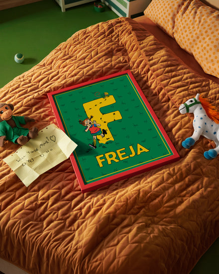 Pippi Longstocking name poster with the letter F and the name Freja placed on a neatly made bed in a bright kids’ room.