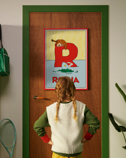 Pippi Longstocking personalised poster featuring the letter R hanging on a door, with a child curiously looking at the artwork.