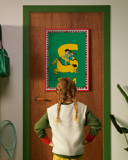 Pippi Longstocking personalised poster featuring the letter S hanging on a door, with a child curiously looking at the artwork.