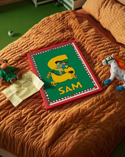 Pippi Longstocking name poster with the letter S and the name Sam, placed on a neatly made bed in a bright kids’ room.