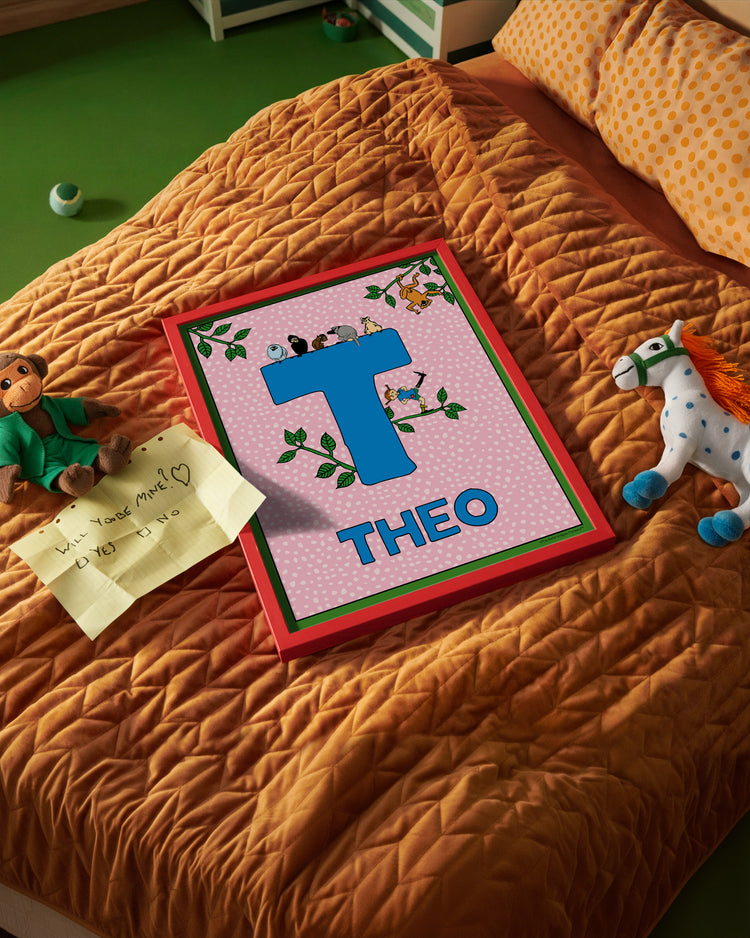 Pippi Longstocking name poster with the letter T and the name Theo, placed on a neatly made bed in a bright kids’ room.