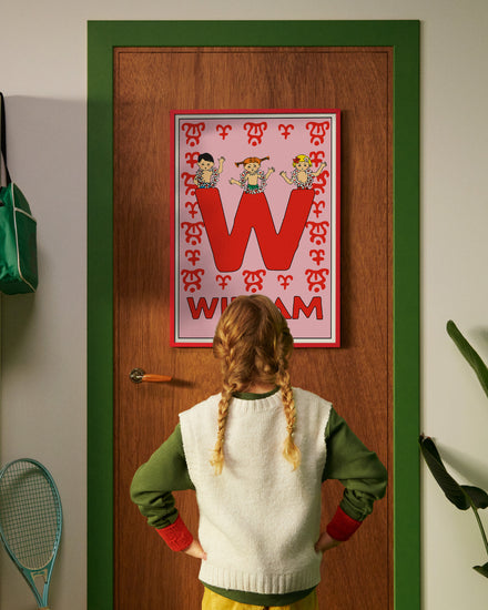 Pippi Longstocking personalised poster featuring the letter W hanging on a door, with a child curiously looking at the artwork.