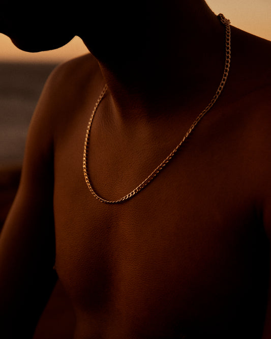 Bare chested man covered in goose bumps and wearing a gold chain necklace.