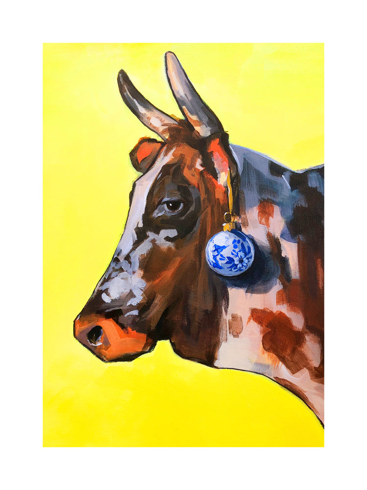 Profile portrait of a bull with a blue Christmas ornament hanging from its ear.