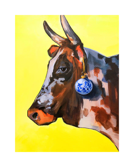 Profile portrait of a bull with a blue Christmas ornament hanging from its ear.