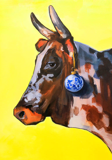 Profile portrait of a bull with a blue Christmas ornament hanging from its ear.