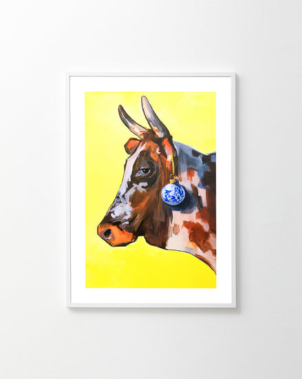 Profile portrait of a bull with a blue Christmas ornament hanging from its ear.