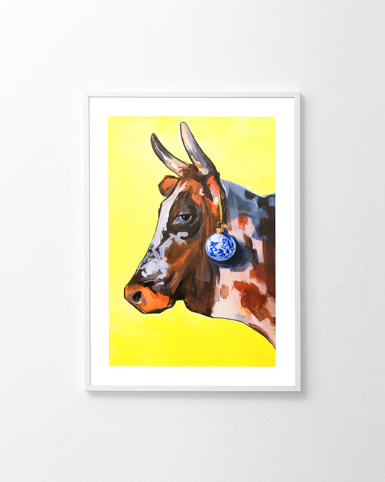Profile portrait of a bull with a blue Christmas ornament hanging from its ear.