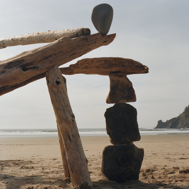 Sculpture made from stones and driftwood on a sandy beach.
