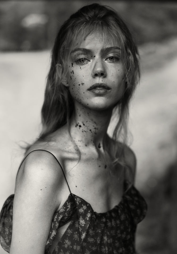 Portrait of a woman in a summer dress with dirt stains on her face.
