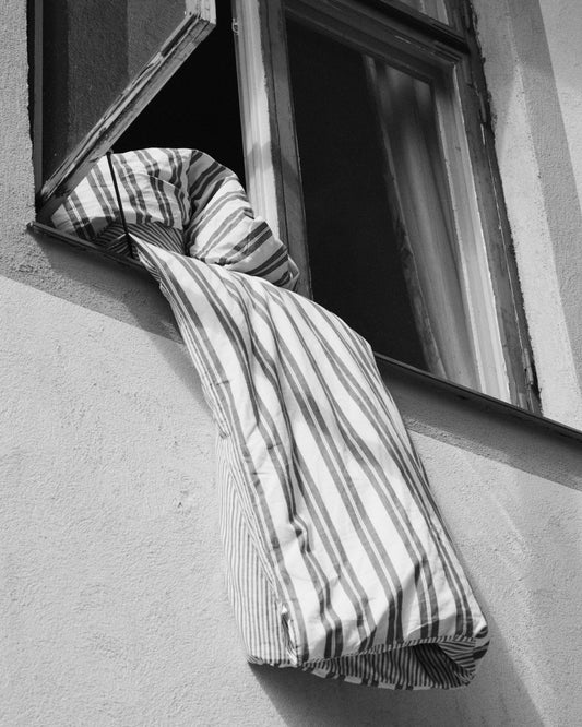 Striped sheets hanging out from an open window.