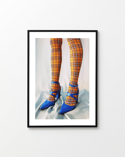 Legs wearing checkered mustard yellow stockings and high heeled blue sandals.
