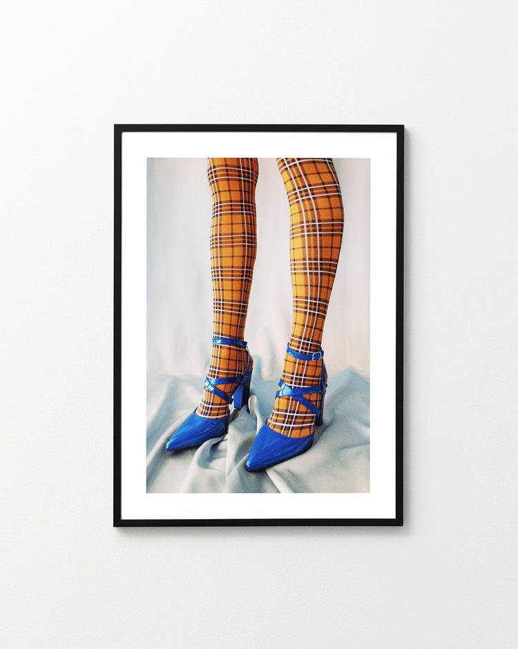 Legs wearing checkered mustard yellow stockings and high heeled blue sandals.