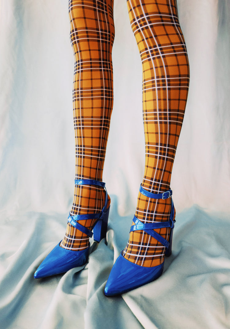 Legs wearing checkered mustard yellow stockings and high heeled blue sandals.