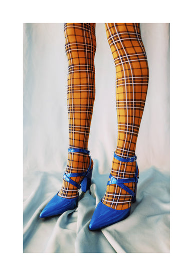 Legs wearing checkered mustard yellow stockings and high heeled blue sandals.