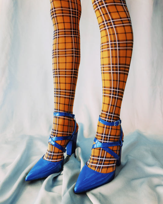 Legs wearing checkered mustard yellow stockings and high heeled blue sandals.