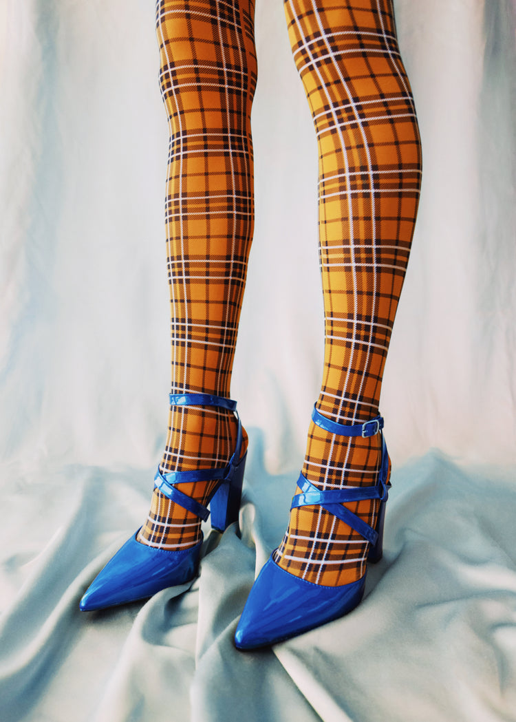 Legs wearing checkered mustard yellow stockings and high heeled blue sandals.
