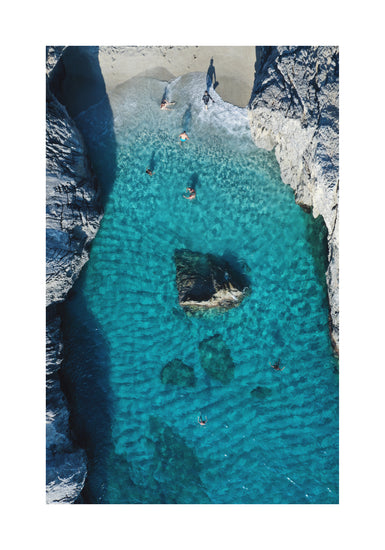 Turquoise natural pool between two cliff walls with people playing by the shore.