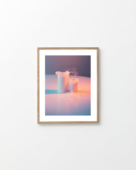 Two recently blown out candles on a white table.