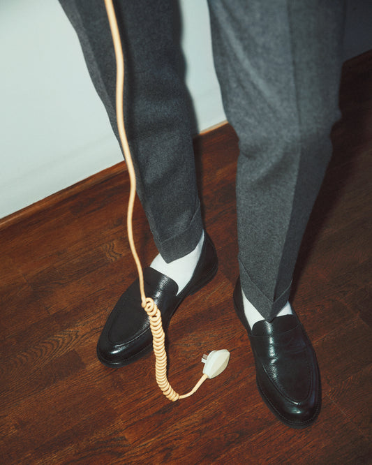 A man with dress shoes and slacks holding a yellow landline.