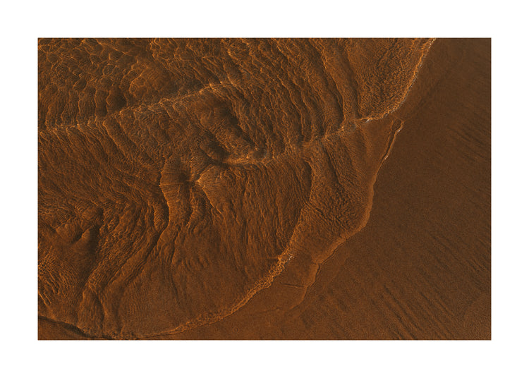 Waves of clear waters softly curling over a sandy shore.