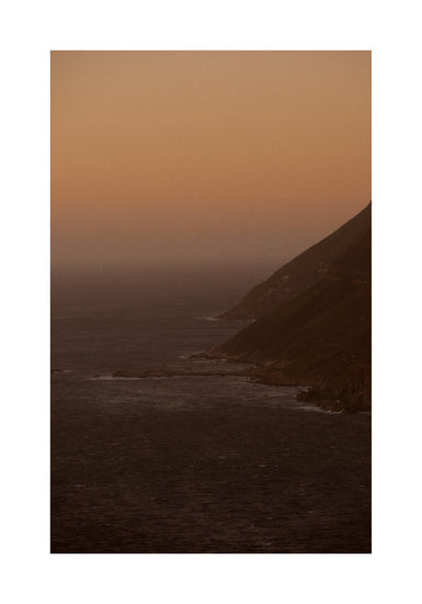 Coastline with a mountain towering along the shoreline during sunrise.