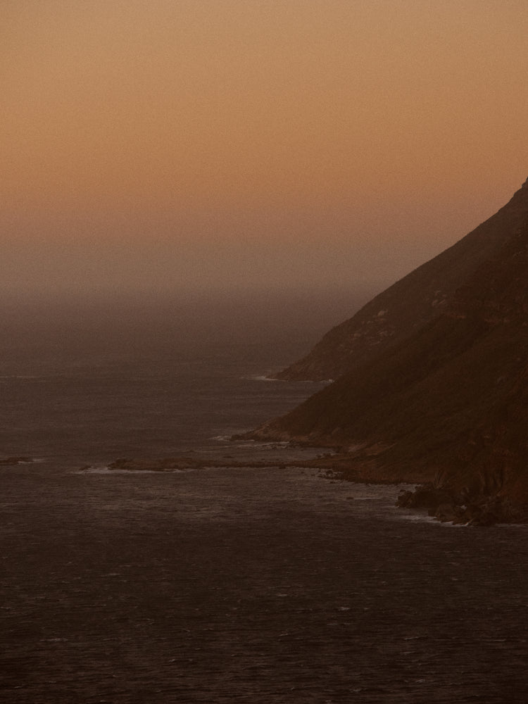 Coastline with a mountain towering along the shoreline during sunrise.