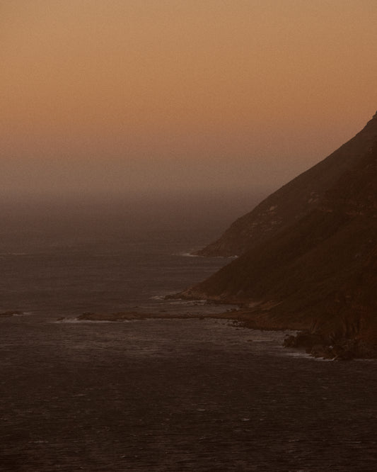 Coastline with a mountain towering along the shoreline during sunrise.