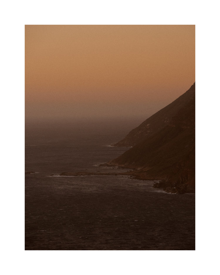 Coastline with a mountain towering along the shoreline during sunrise.