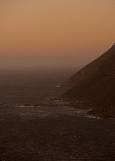 Coastline with a mountain towering along the shoreline during sunrise.