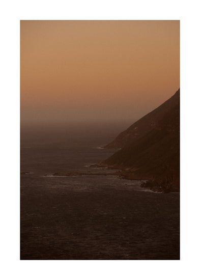 Coastline with a mountain towering along the shoreline during sunrise.