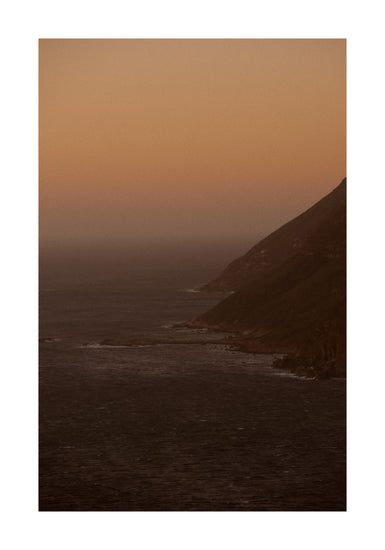 Coastline with a mountain towering along the shoreline during sunrise.