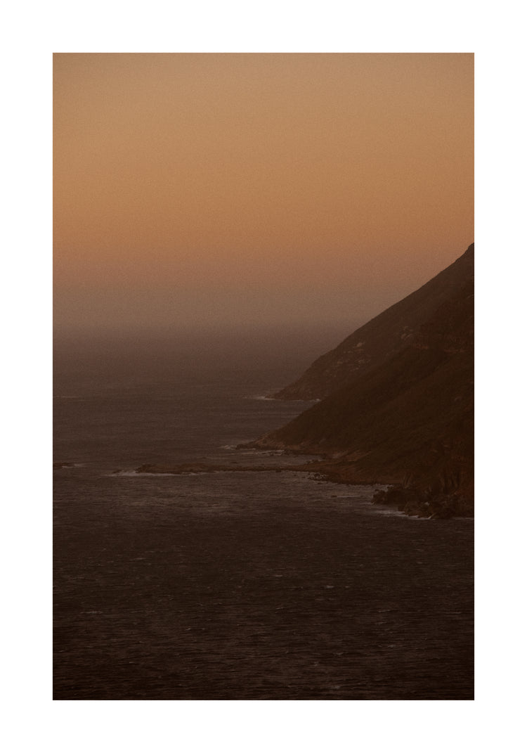 Coastline with a mountain towering along the shoreline during sunrise.