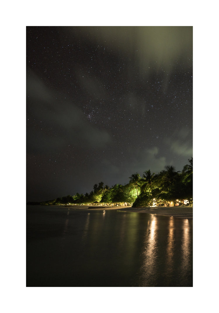 Paradise island with palm trees and white sand under a star strewn sky.