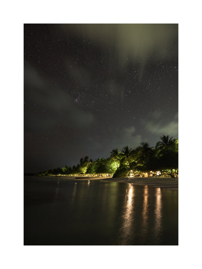 Paradise island with palm trees and white sand under a star strewn sky.