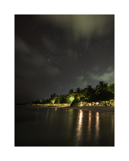 Paradise island with palm trees and white sand under a star strewn sky.