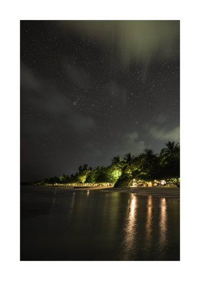Paradise island with palm trees and white sand under a star strewn sky.