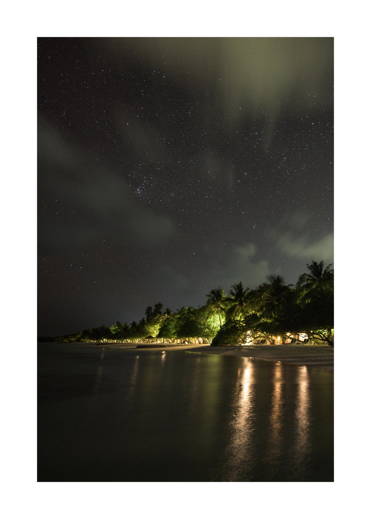 Paradise island with palm trees and white sand under a star strewn sky.