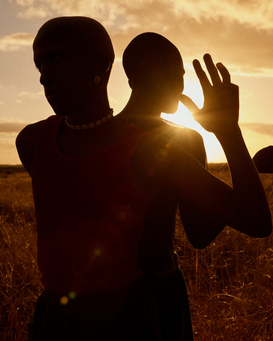 Two brothers standing back-to-back on an open field in the gazing sun.