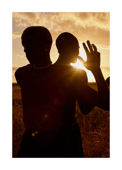 Two brothers standing back-to-back on an open field in the gazing sun.