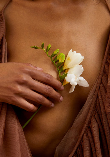 A woman wearing a low-cut dress covering her chest with a white flower.