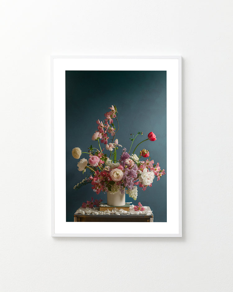 The Spring Ballet Poster features a framed photograph of a floral arrangement with pink, white, and purple flowers against a dark teal background, displayed on a wooden table.