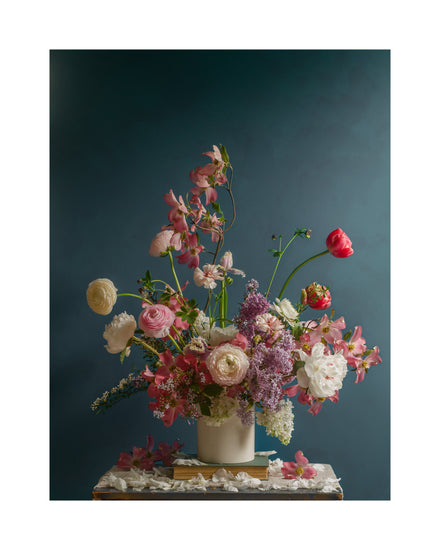 The Spring Ballet Poster showcases a vibrant and elegant display of pink and white roses, lilacs, and red tulips in a colorful floral arrangement within a white vase on a textured surface set against a teal background.